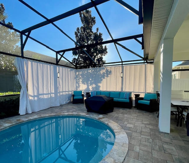 White privacy curtains around pool with teal furniture