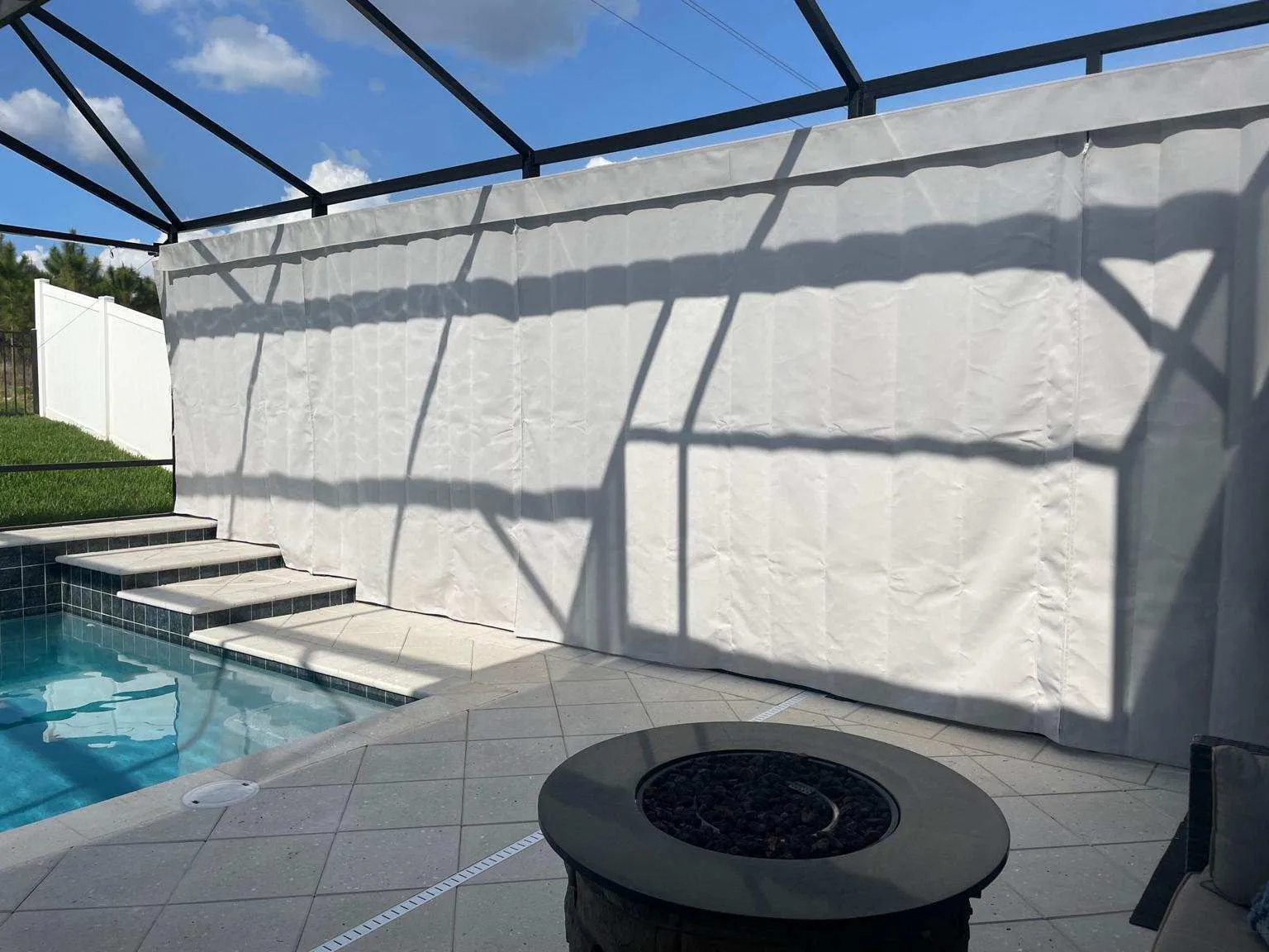 Striped curtains in pool enclosure with fire pit