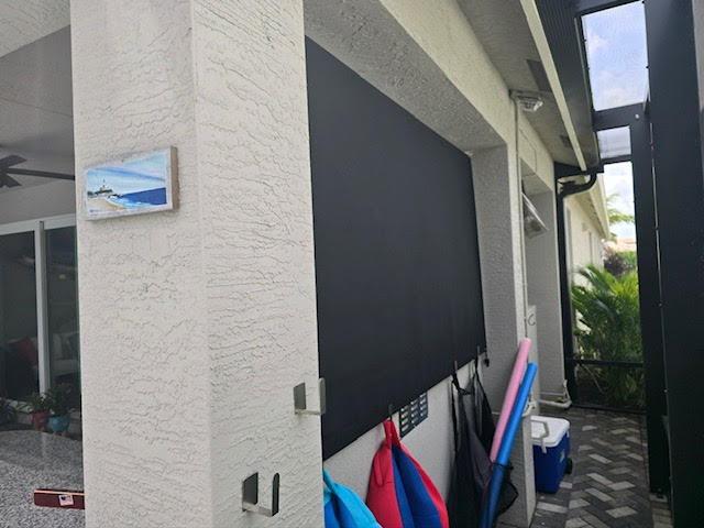 Roller shade protecting outdoor TV from sun glare