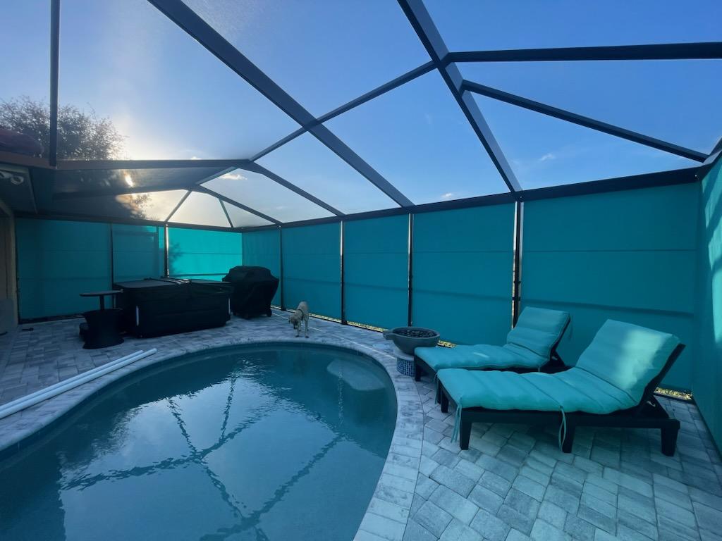 Teal roller shades around pool enclosure at sunset