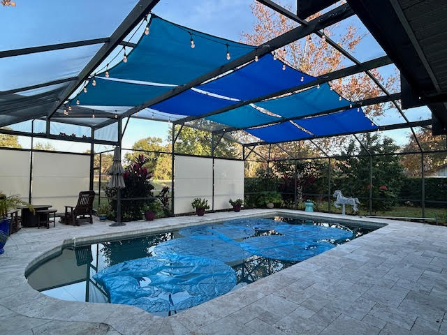 Blue shade sails over pool with roller shades on sides